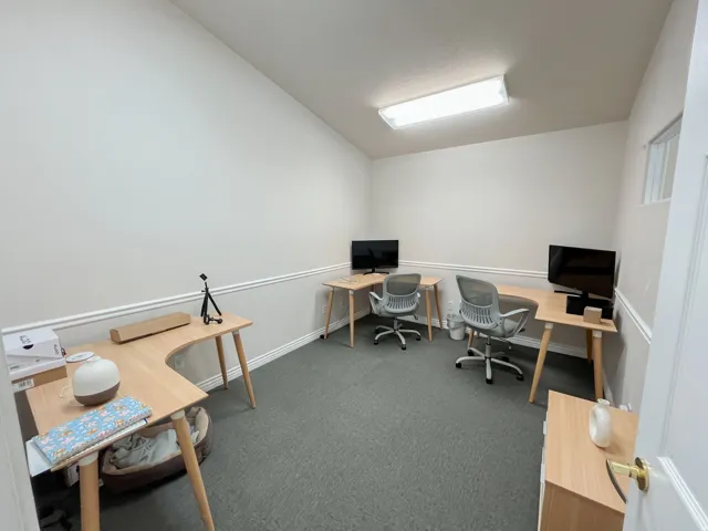 Dedicated office space featuring a vaulted ceiling, neutral wall tones, chair rail molding, and grey carpet