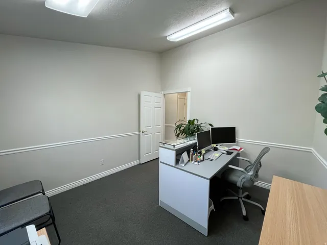 Professional office space featuring light-toned walls with chair rail molding and dark gray carpet flooring