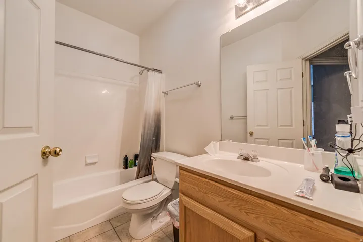 Full bathroom featuring a white tub-shower combination, a white toilet, and a wood-finish vanity with an integrated sink and mirror