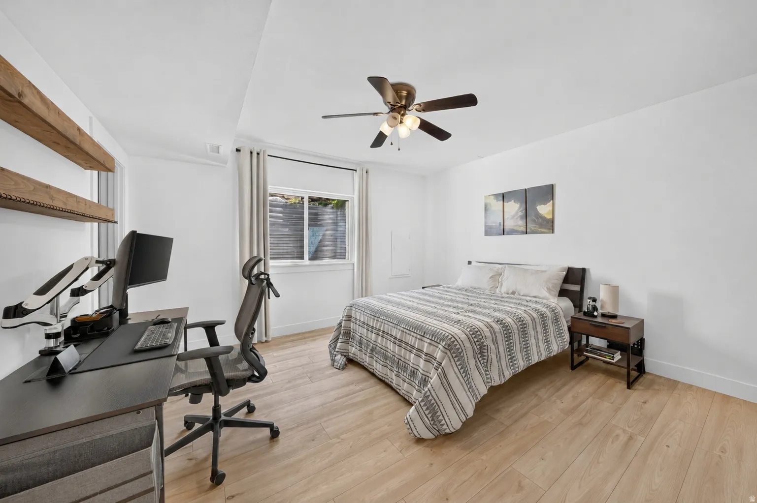 Bedroom featuring light wood-finish flooring, a ceiling fan with integrated lighting, and a recessed window