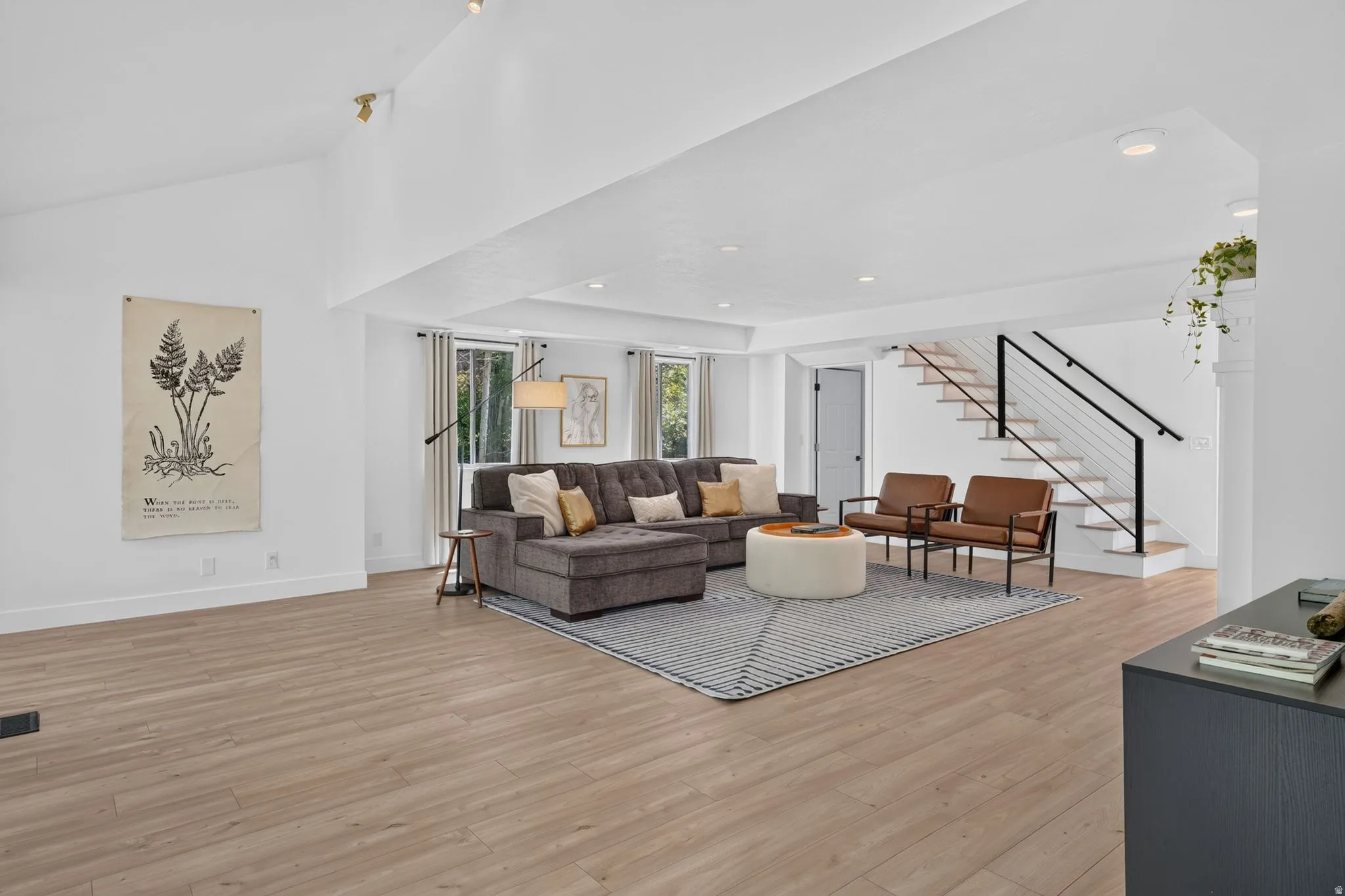 Open-concept living space featuring light wood-finish flooring, white walls, and recessed lighting