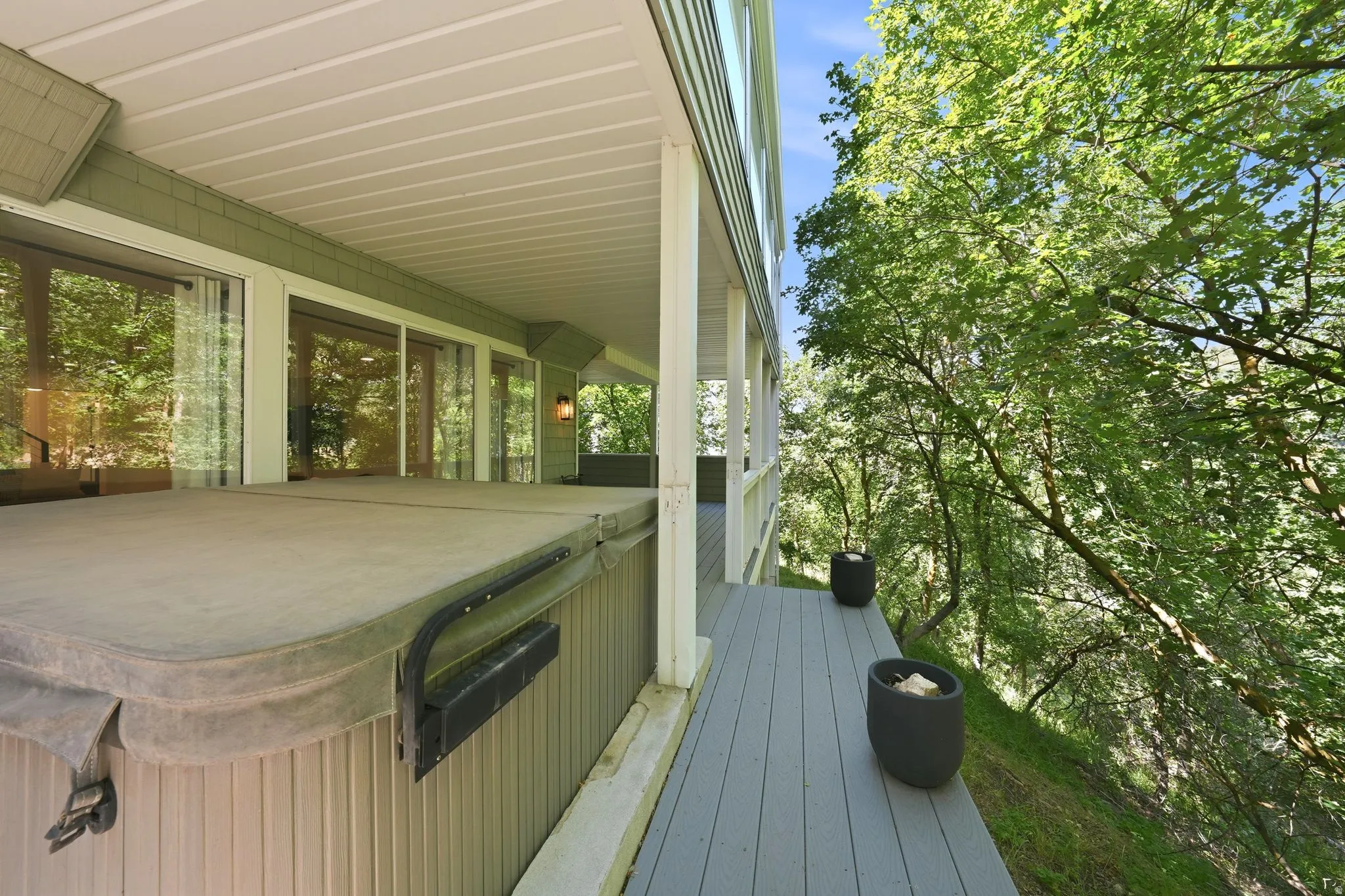Covered outdoor deck with a hot tub and wood-finish decking