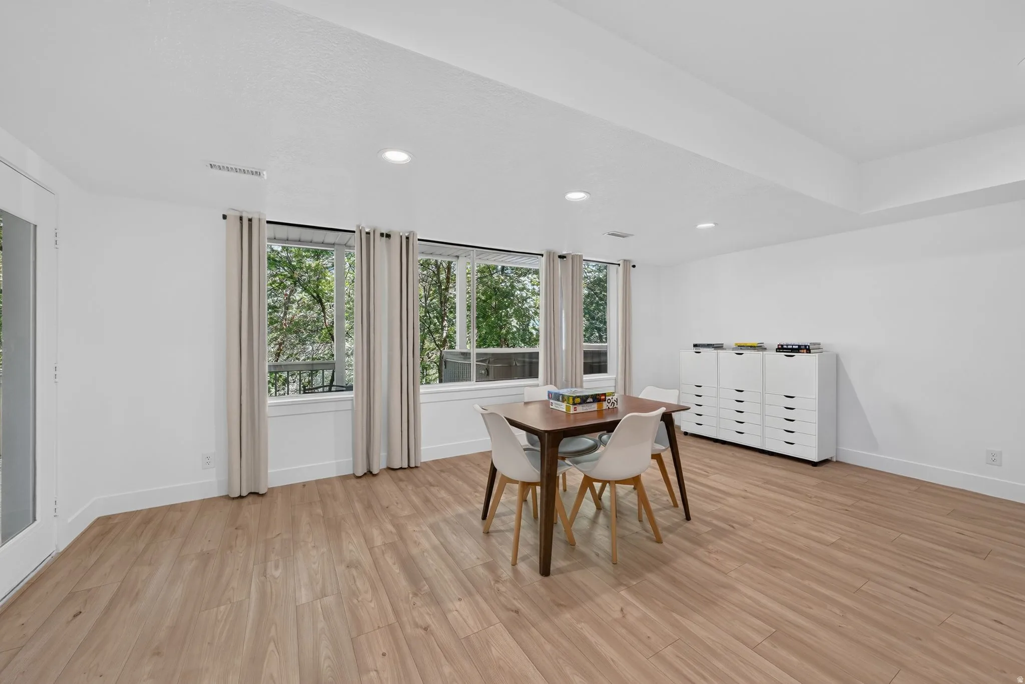 Spacious room featuring wood-finish flooring, white walls, and recessed lighting