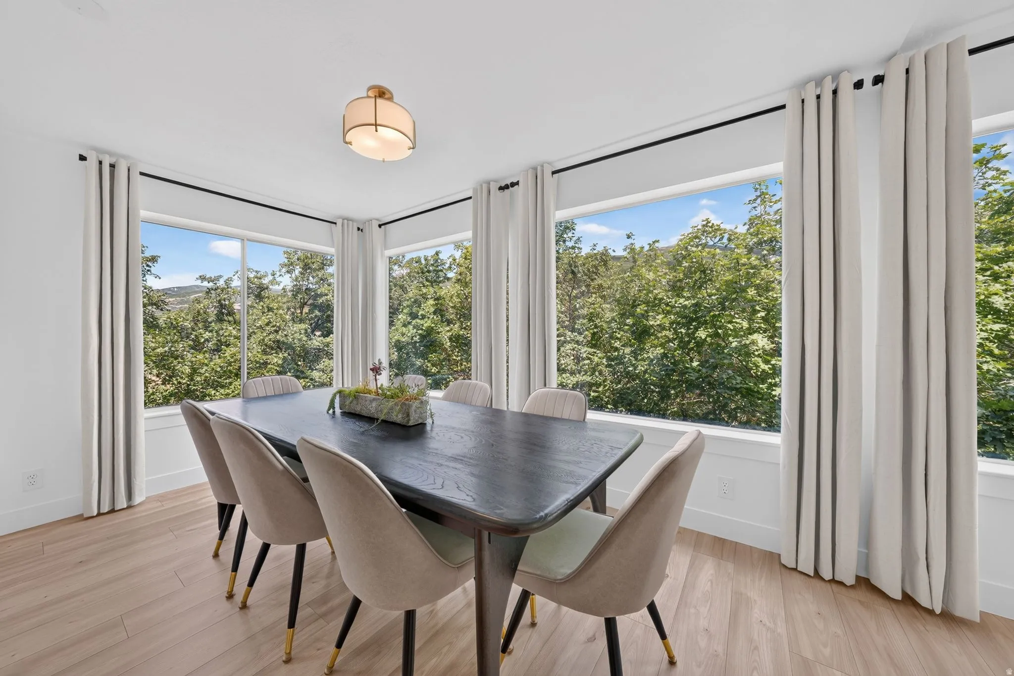 Dining area featuring expansive windows, wood-finish flooring, a contemporary semi-flush mount light fixture, and white walls