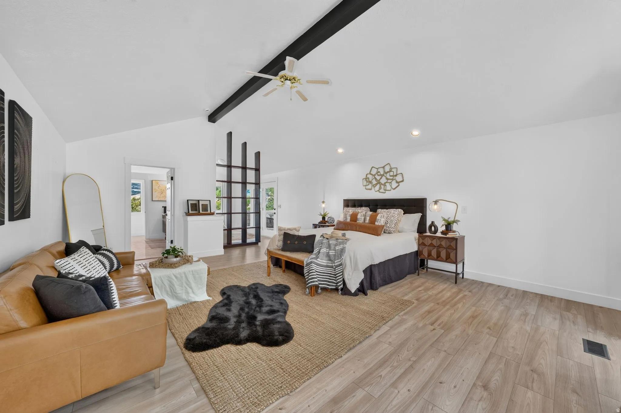 Spacious room featuring vaulted ceilings with exposed dark beams, wood-finish flooring, and recessed lighting