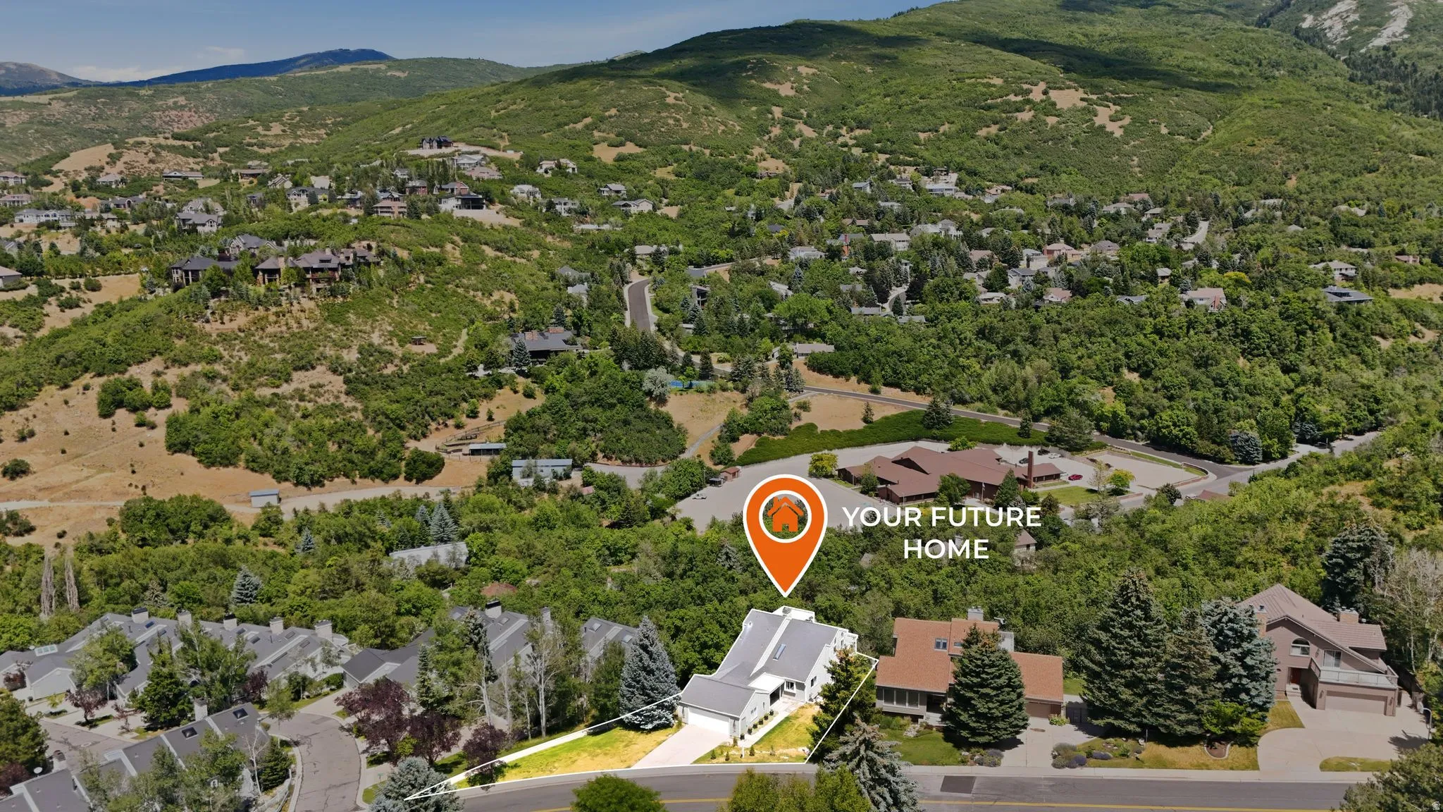 Aerial perspective showcasing a property with a multi-level roofline, situated within a verdant, mountainous landscape