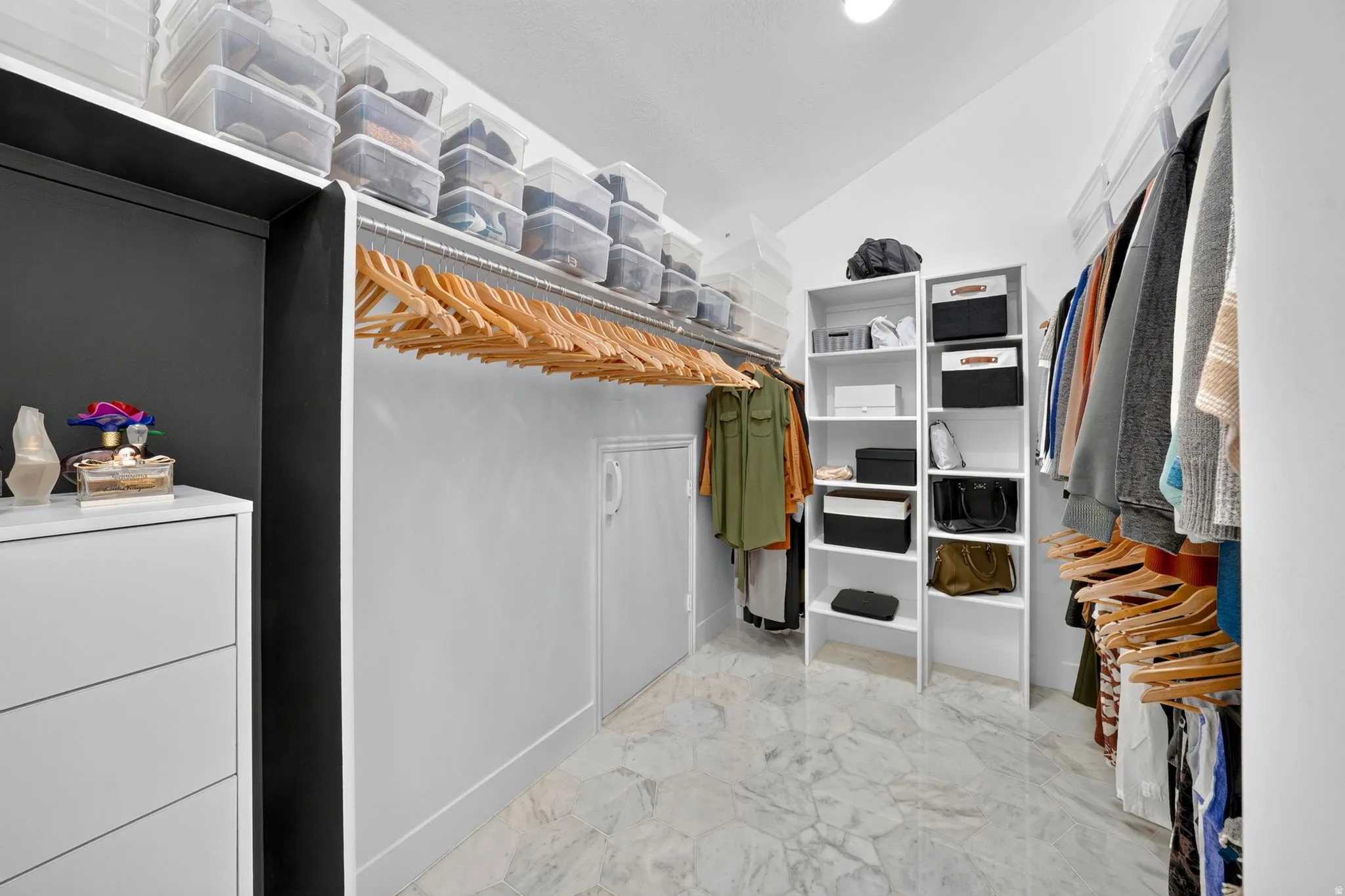 2nd Floor Spacious walk-in closet featuring light-toned tile flooring, extensive hanging rods, multiple built-in shelving units, and a dedicated dresser space