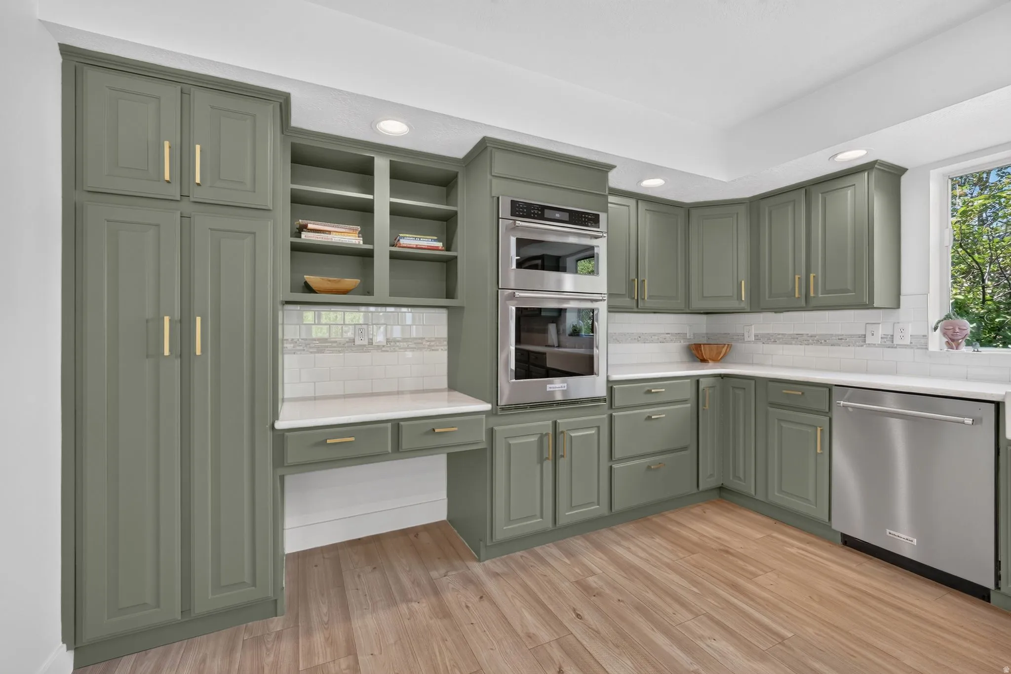 Kitchen featuring wood-finish flooring, recessed lighting, and sage green cabinetry with gold-tone hardware