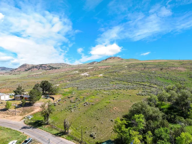 Expansive rural landscape featuring a single-story residence, mature trees, and mountainous terrain