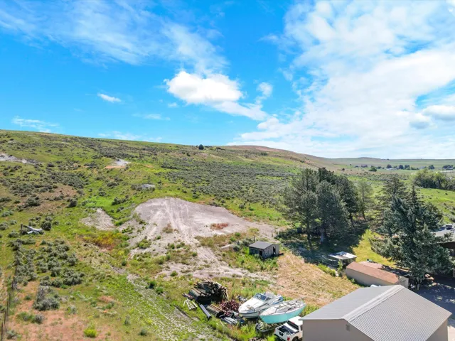 Expansive hillside property featuring diverse terrain, mature trees, and outbuildings