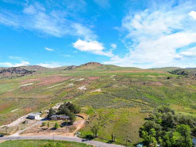 Expansive lot featuring a single-story residence with a detached garage, surrounded by rolling hills and mature trees