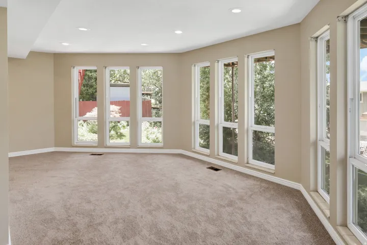 View 3 Spacious primary bedroom featuring extensive window placement, recessed ceiling lighting, light beige wall paint, white baseboards, views
