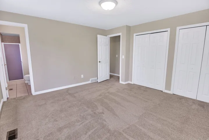 Spacious carpeted room featuring double white bi-fold closets, through to ensuite  3/4 bath