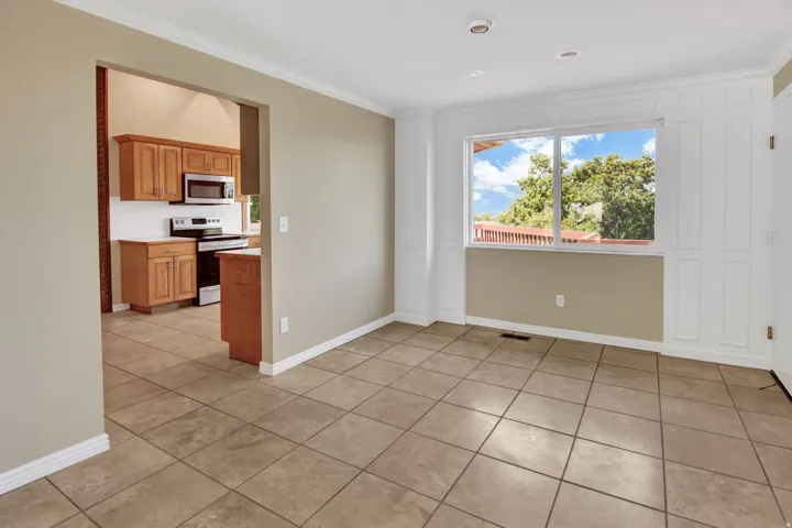 Formal dining with large view window with white paneling. Access garage from the far right of photo. View into kitchen
