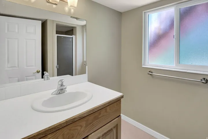 Bathroom featuring a wood-finish vanity with an integrated sink and a white countertop