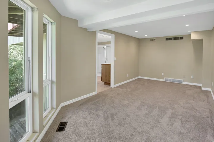 Second primary suite with view into full bathSpacious room featuring neutral carpeting and wall paint