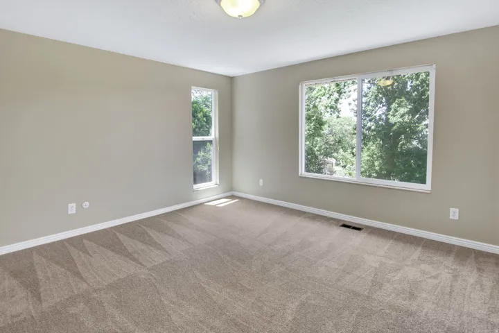 Spacious room featuring neutral wall paint, light tan carpeting