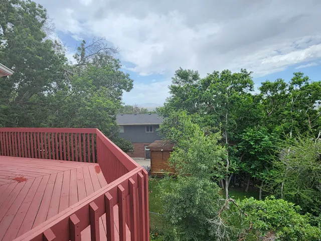 Spacious red-stained wood deck with slatted railings. Some valley view
