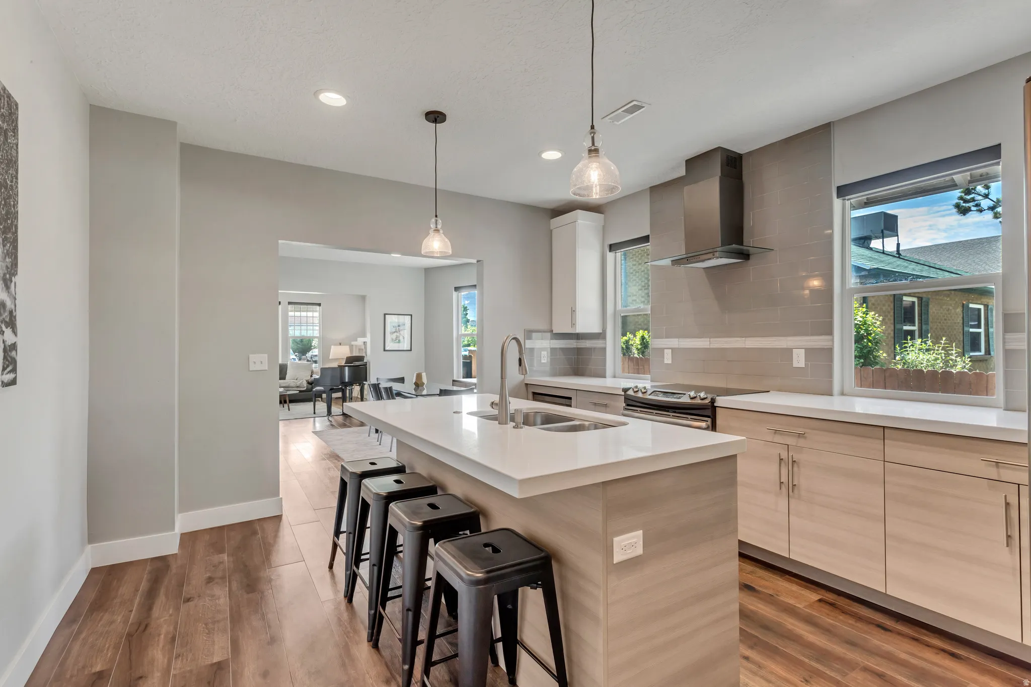 Contemporary kitchen featuring a large center island with seating, stainless steel appliances, a tiled backsplash, and recessed lighting