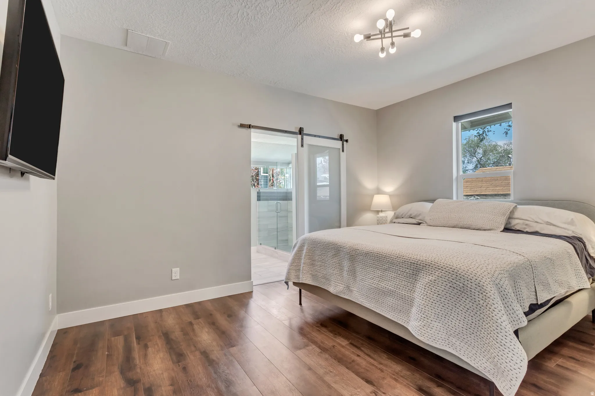 Bedroom featuring wood-finish flooring, a contemporary ceiling light fixture, and a window with exterior visibility