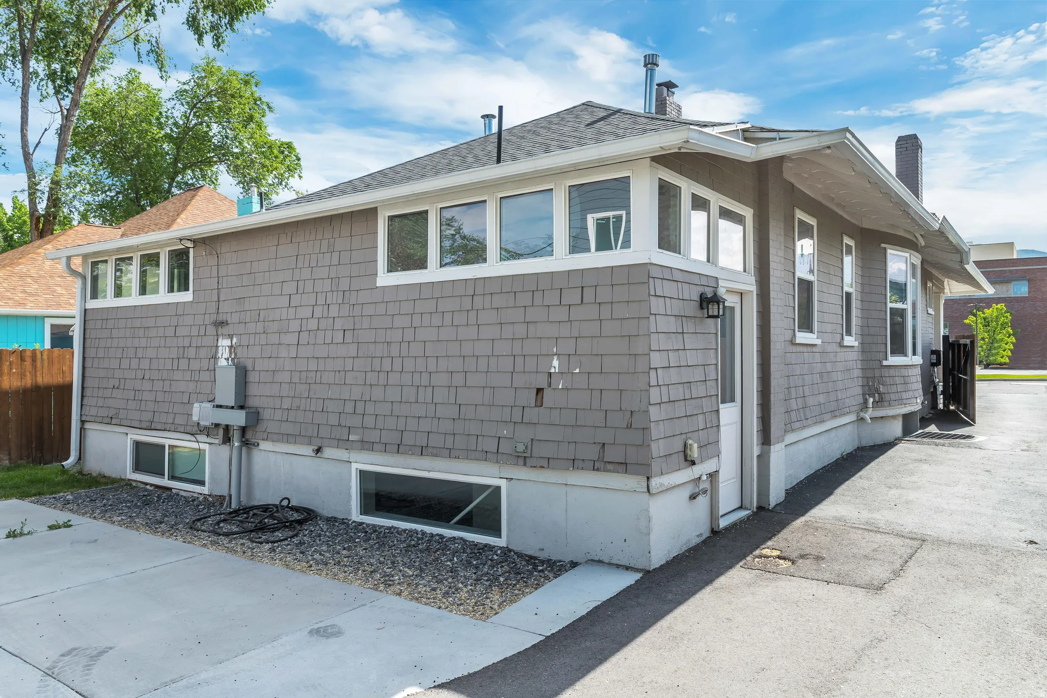 Exterior featuring shingle siding, a lower foundation, and multiple windows