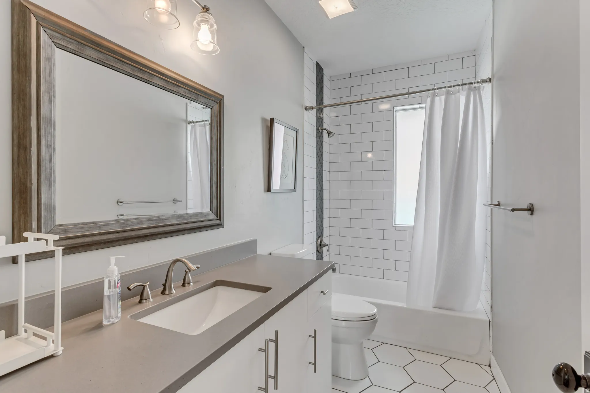 Contemporary bathroom featuring a vanity with an integrated sink and brushed nickel faucet, a large framed mirror, and two-light fixture