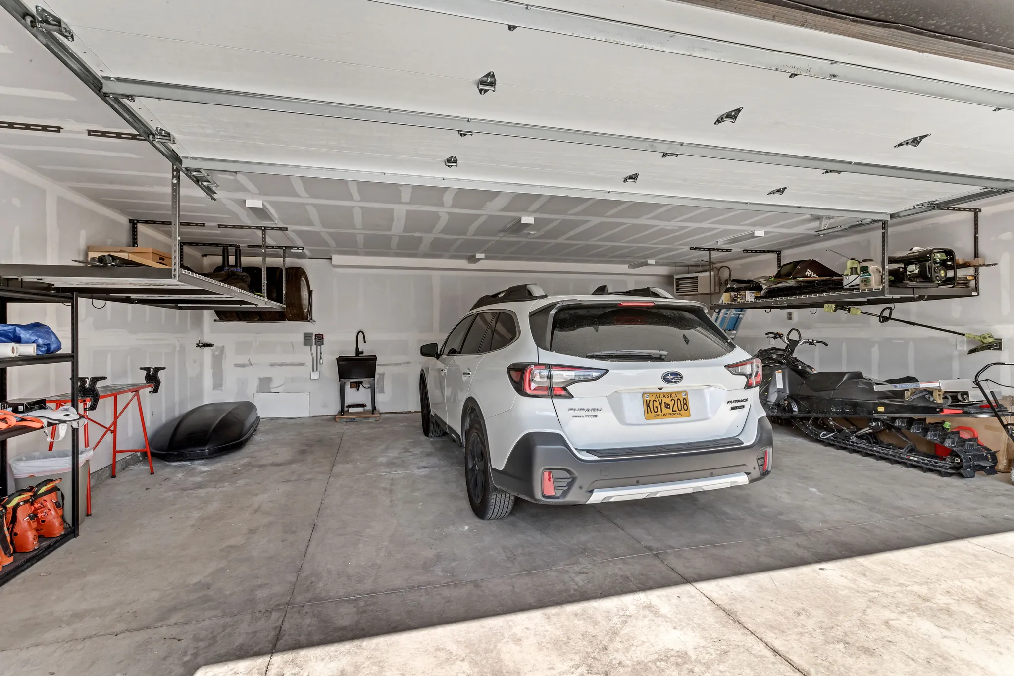 Spacious garage featuring a concrete floor, finished walls, and multiple overhead storage racks