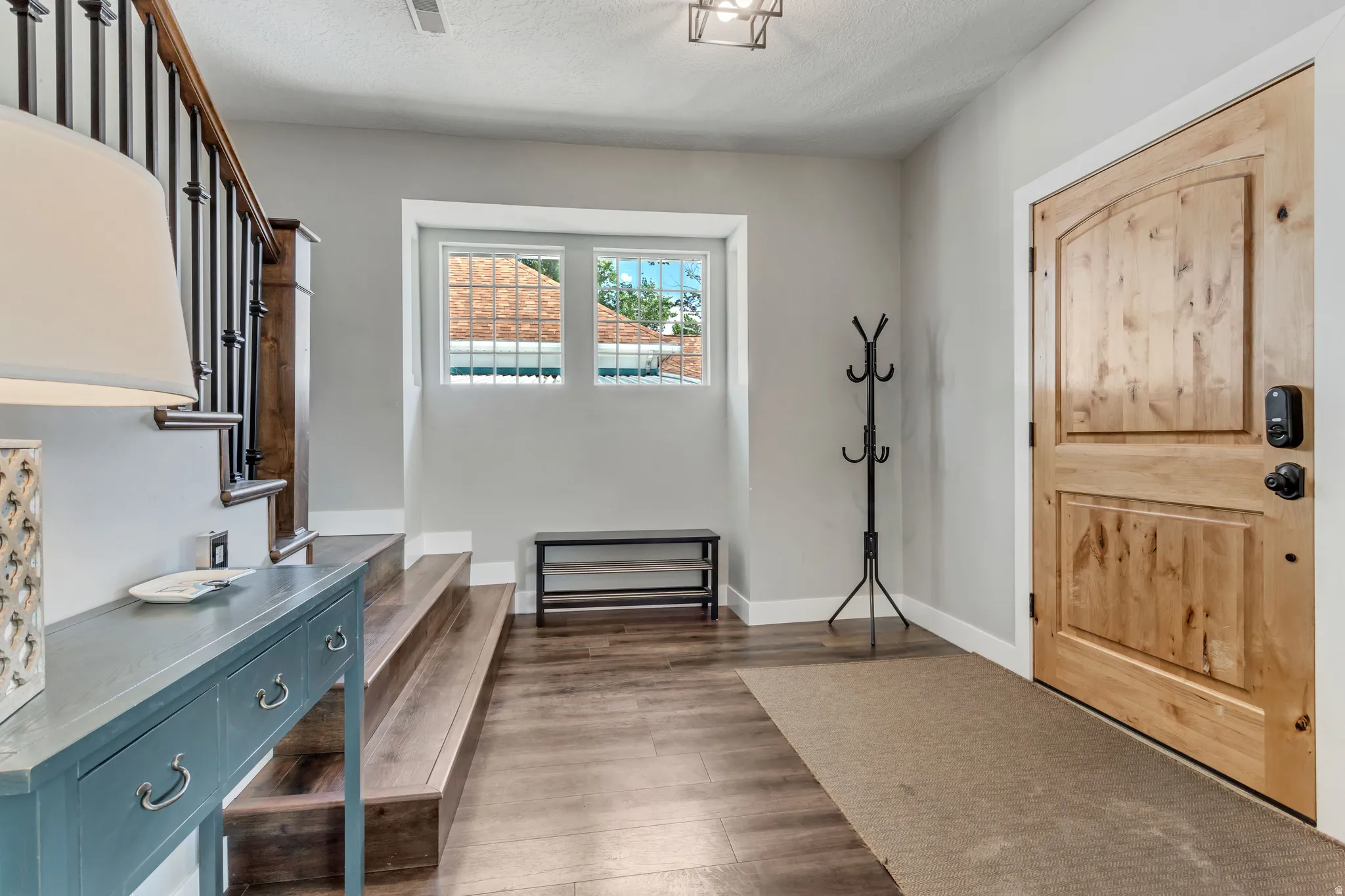 Entryway featuring wood-finish flooring, a solid wood entry door, and a staircase with dark wood treads and wrought iron balusters