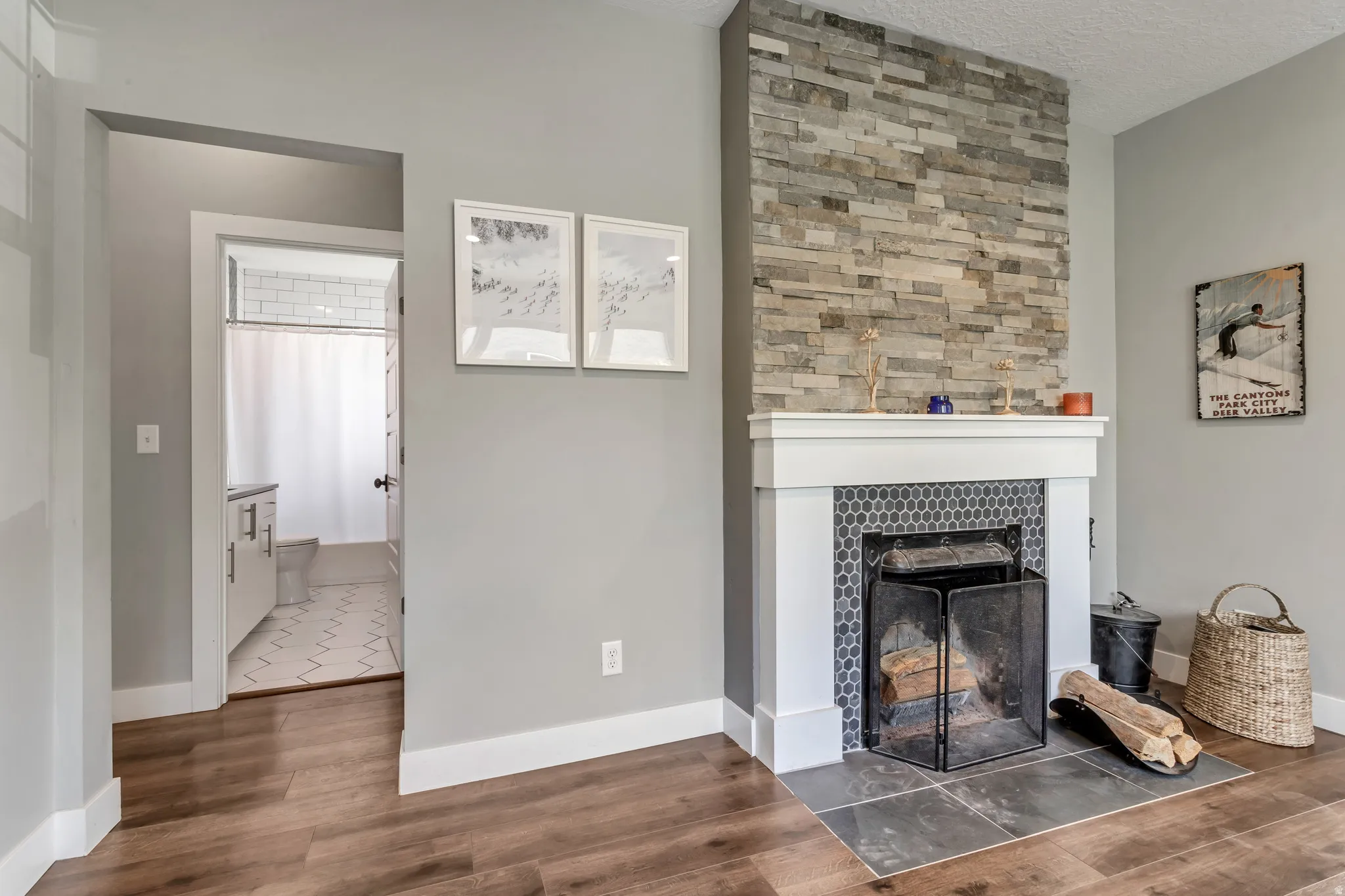 Stone-clad fireplace featuring a white mantel, hexagonal tile surround, and slate hearth