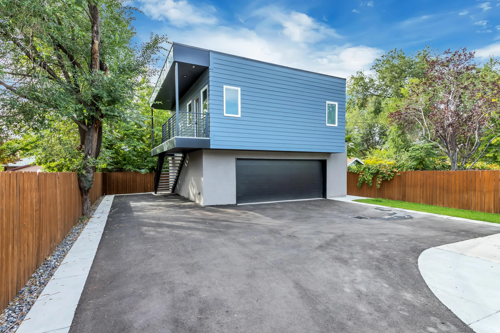 Modern multi-level exterior with blue siding and a dark garage door