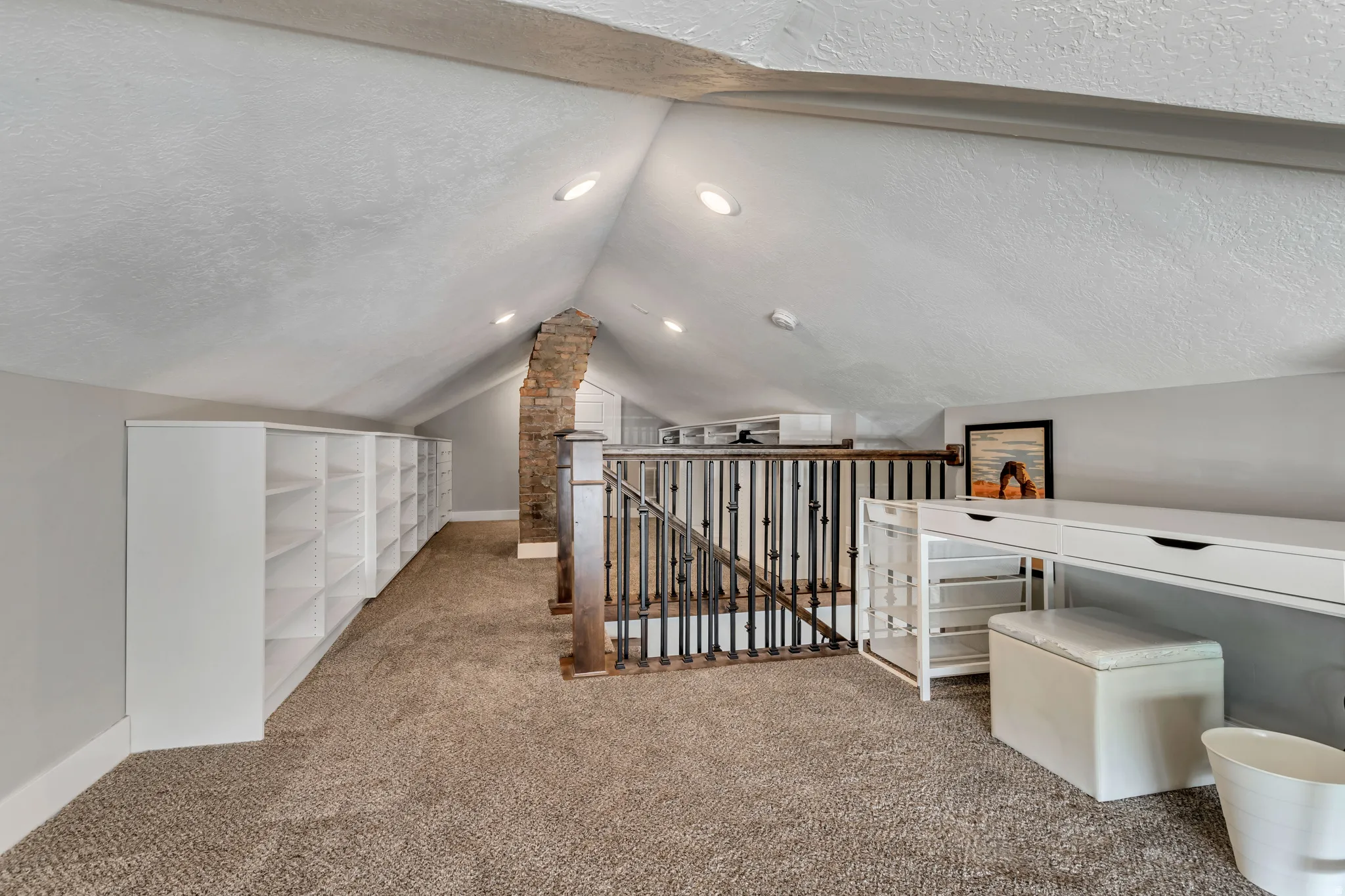 Loft space featuring sloped ceilings with recessed lighting, plush carpeting, a partial brick column, and built-in white shelving