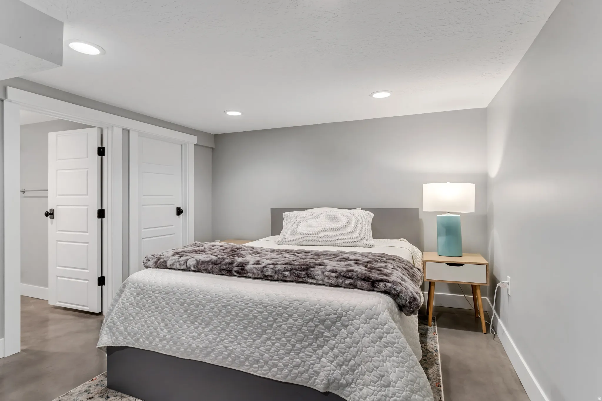 Recessed lighting illuminates this room featuring light gray walls, white trim, and a built-in closet with paneled bifold doors