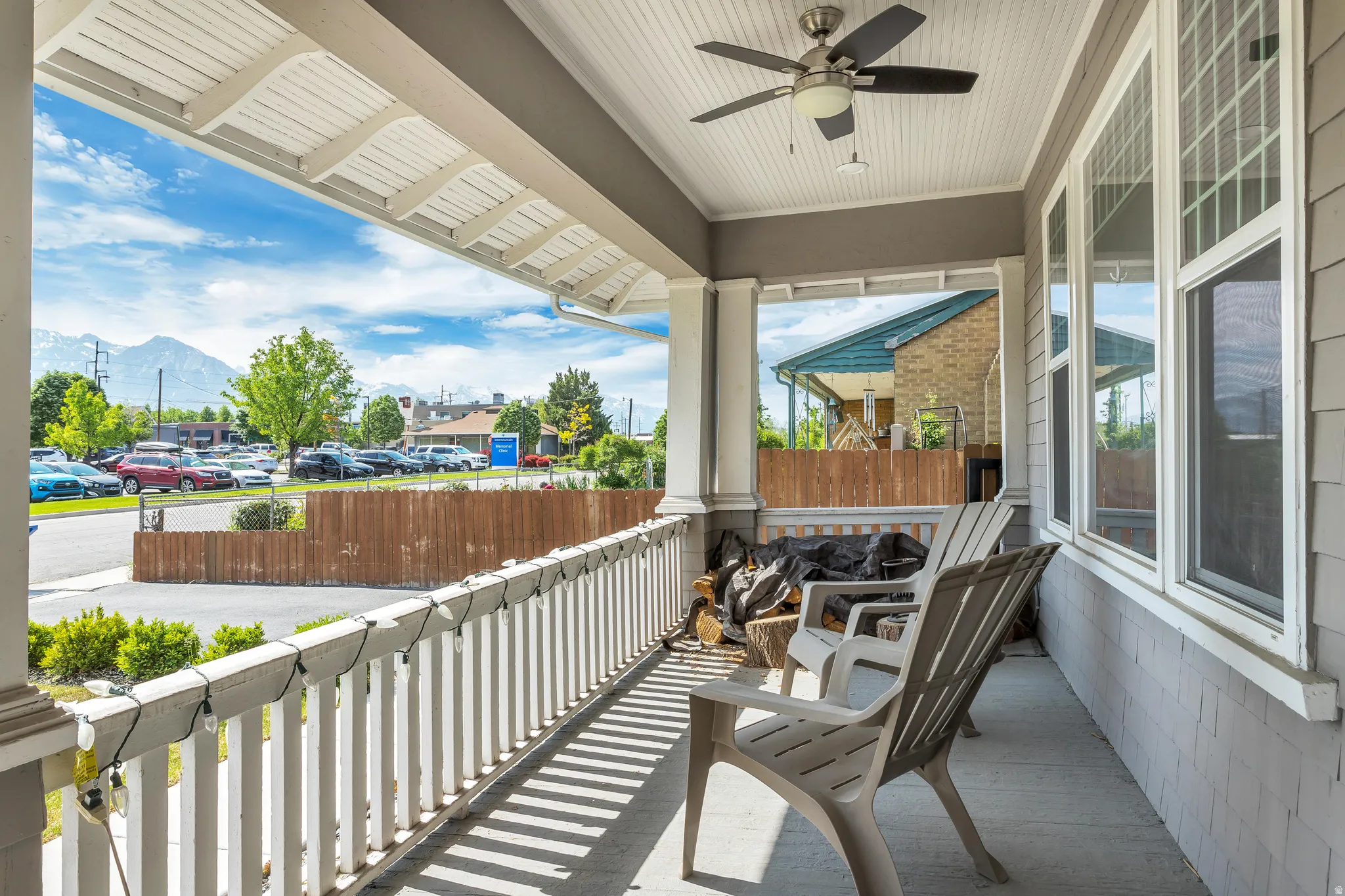 Covered porch featuring a beadboard ceiling with a ceiling fan, white baluster railing, and an adjacent multi-pane window