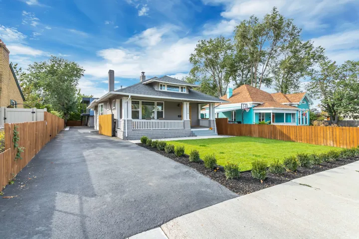 Craftsman-style exterior with a covered front porch, a long paved driveway, and a front lawn with foundational shrubs