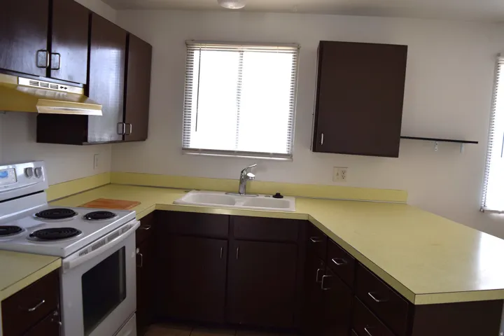 Kitchen featuring dark wood-finish cabinetry, light yellow countertops, and a white electric range
