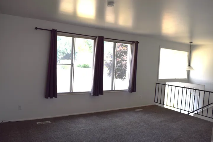 Living area featuring carpet flooring, white walls, and multiple windows