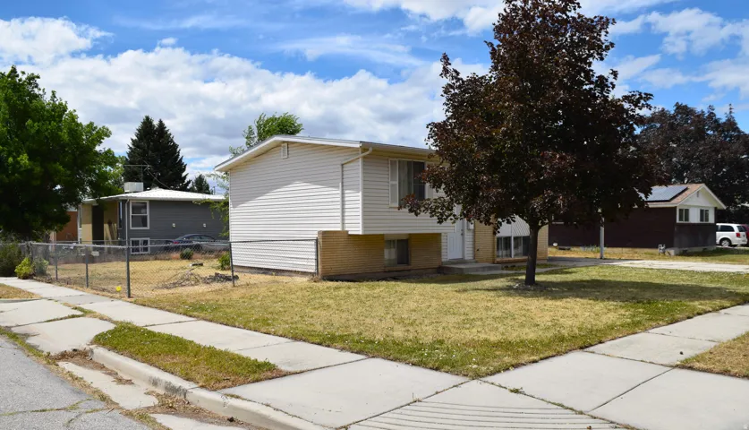 Split-level residence featuring light-colored siding and a brick base