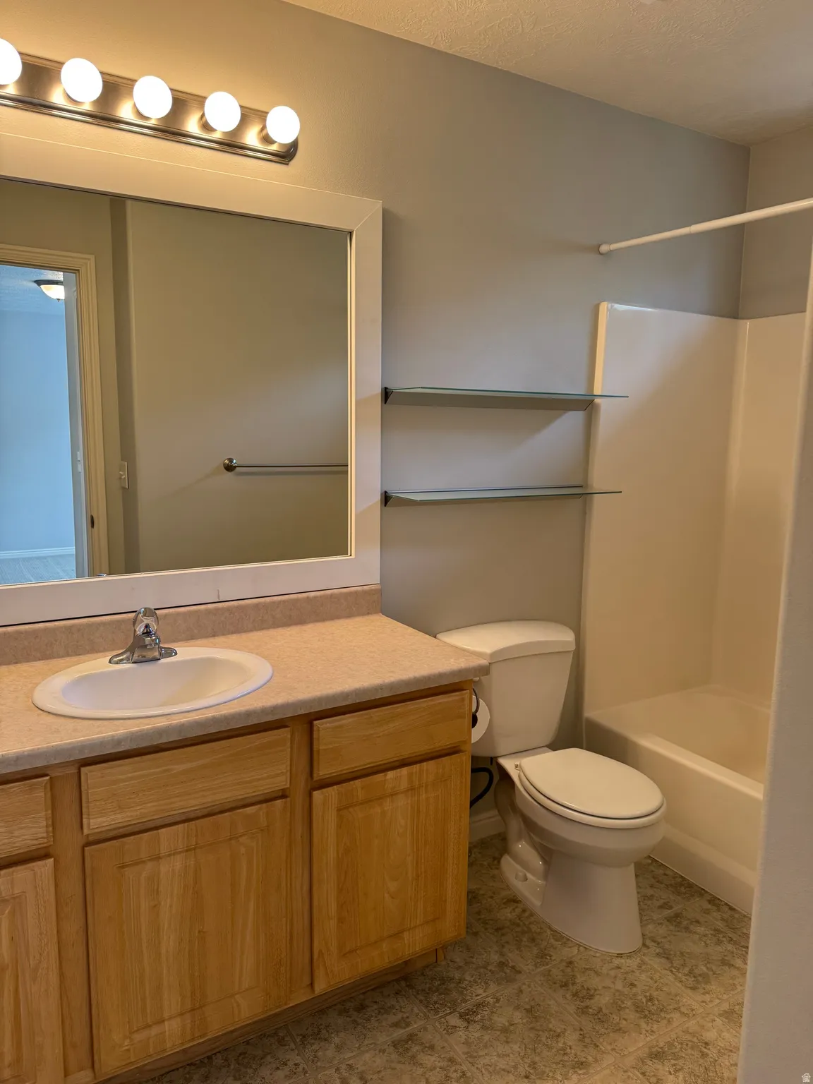 En-suite primary bath with a large vanity and countertop and tub-shower combo.