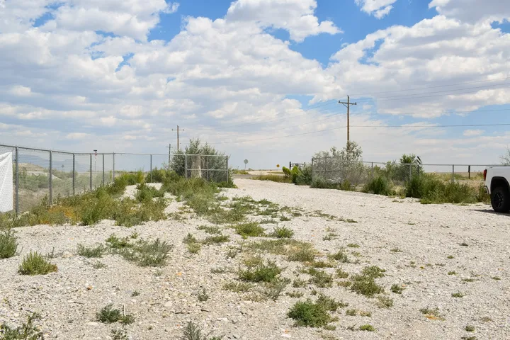 Gravel access road featuring chain link fencing and established vegetation