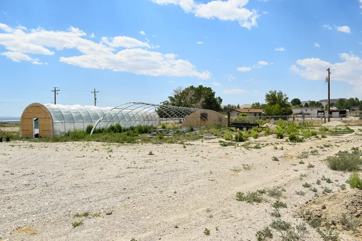 Multiple hoop house structures with clear plastic coverings, one featuring a wood-panel end wall