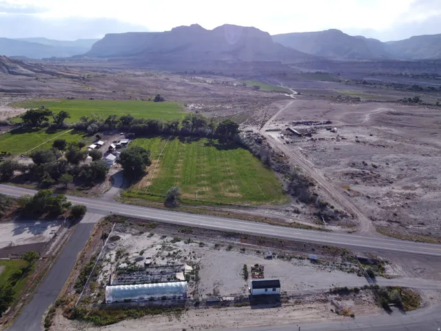 Expansive property featuring a greenhouse structure, a small white building, and agricultural fields