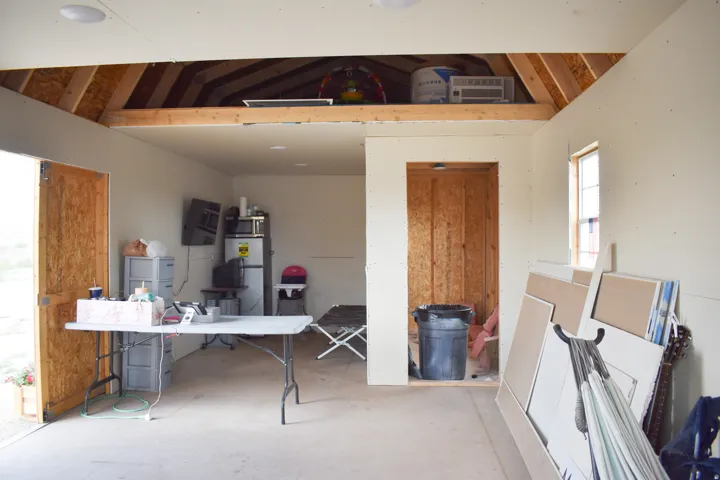 Interior space featuring an exposed wood rafter attic storage area, light-colored walls, and a recessed ceiling light fixture
