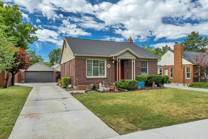 Traditional brick residence featuring a dark shingle roof, a covered entry, and a prominent front lawn