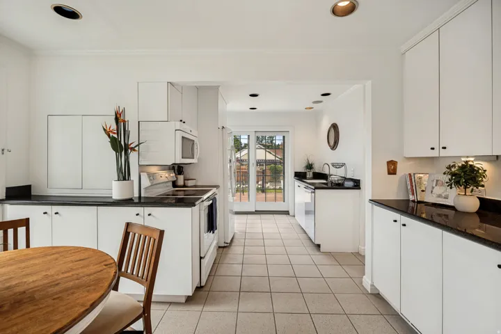 Kitchen featuring white cabinetry, dark countertops, a white electric range, and a built-in microwave