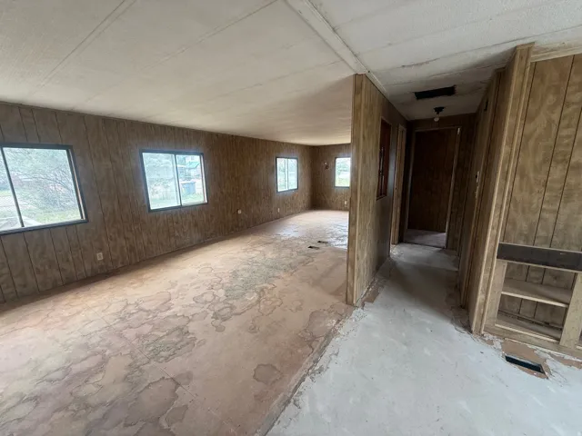 Spacious interior with wall paneling, multiple windows, and exposed subflooring