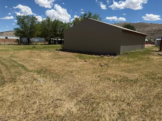 Expansive lot featuring a large metal-sided outbuilding with a pitched roof
