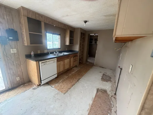 Kitchen featuring a dual basin sink, integrated dishwasher, and upper and lower cabinetry