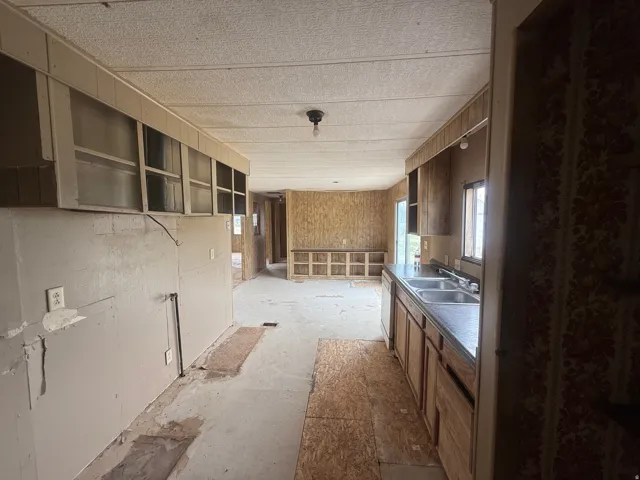 Kitchen space featuring a double basin sink, ample cabinetry, and a textured ceiling