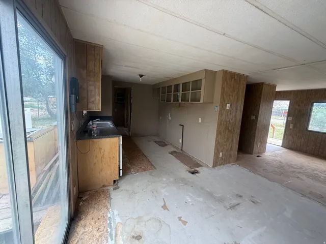 Interior space featuring a sliding glass door, partial kitchen cabinetry, and wood-finish wall panels