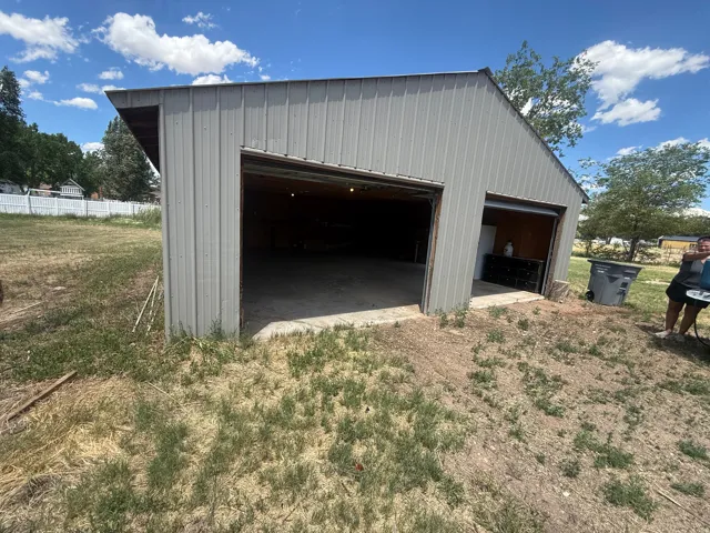 Two-bay metal structure featuring roll-up doors, concrete flooring, and an open interior